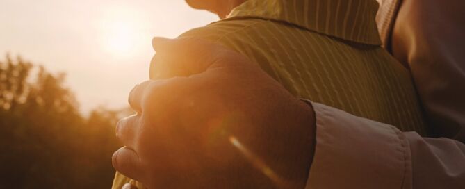 Loving retired Husband Hugging Wife In Park at sunset; retirement community wait list