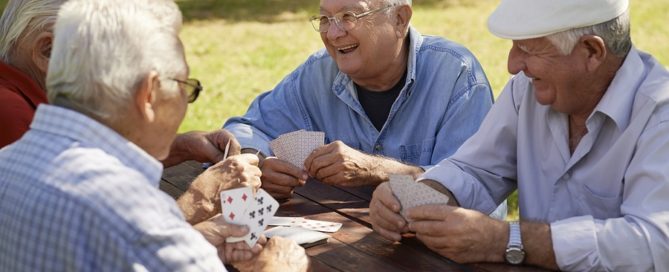 four older men having fun and playing card game at park active seniors