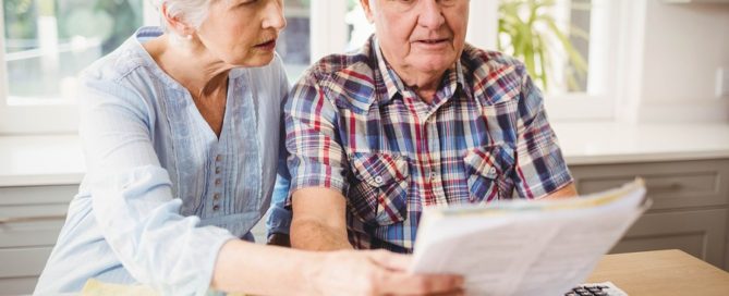 Worried senior couple checking their bills at home