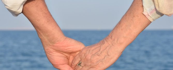 close up Elderly couple holding hands over sea background