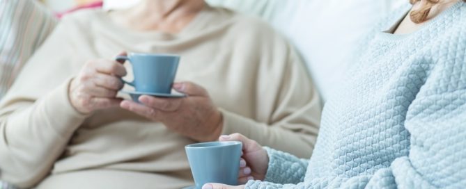 Two elderly women drinking coffee during conversation at home conversation with aging parent