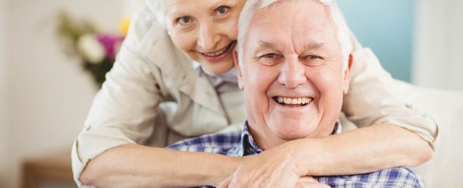 Portrait of senior woman embracing man in living room