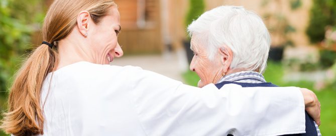 Young carer walking with the elderly woman in the park