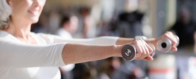 senior wellness health older woman weight training at a gym