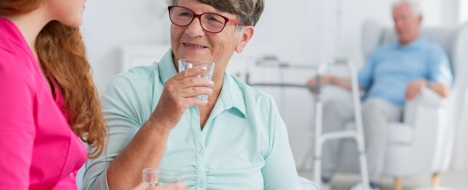 assisted living long term care aide young woman helping an older man and woman