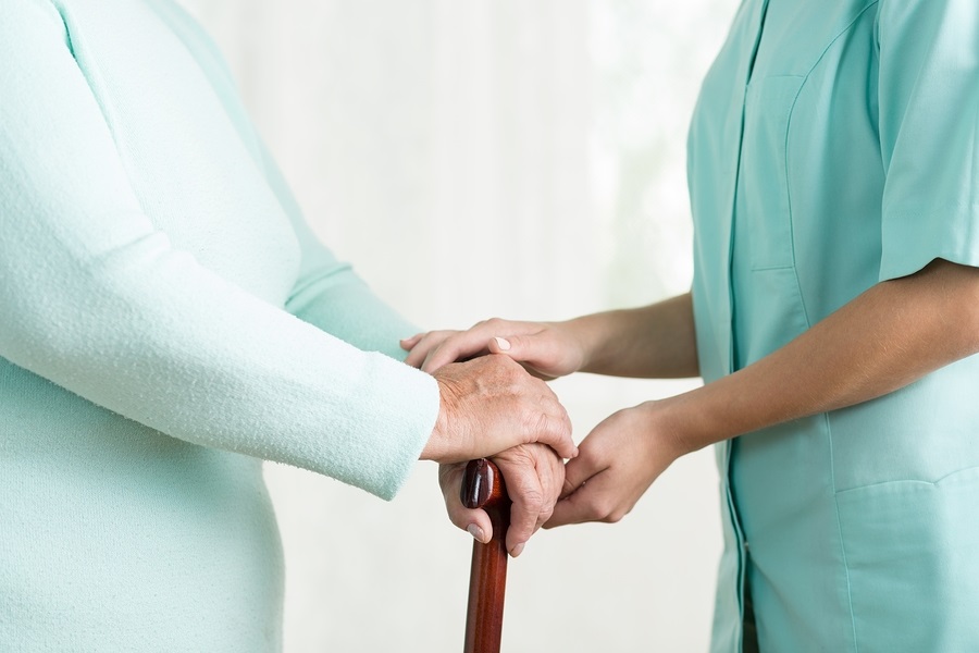 fear about moving to a CCRC close up of nurse helping an older woman with a cane