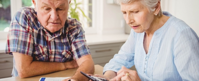 senior couple comparing CCRCs at home with papers and calculator