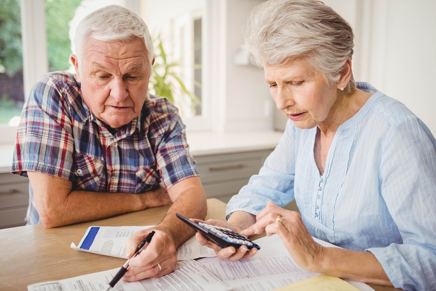 senior couple comparing CCRCs at home with papers and calculator