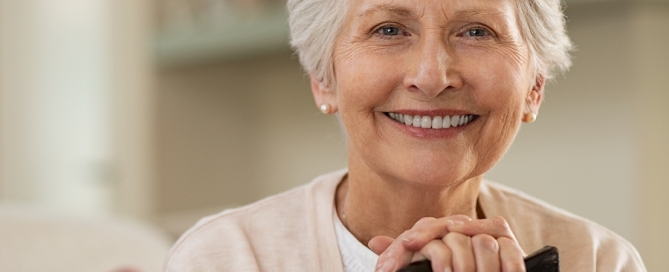 smiling elderly woman in independent living with a cane