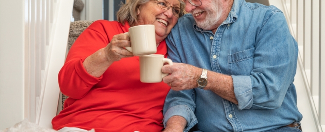 Senior Adult Couple Resting on Stairs with Cups of Coffee Surrounded with Moving Boxes