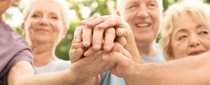 Group of older people putting hands together as symbol of unity