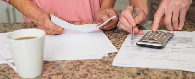Senior couple paying their bills at home in the kitchen