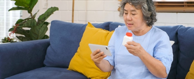 Senior woman holding bottle of pills and smartphone