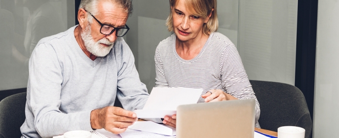 Senior couple reading documents and calculating bills to pay CCRC financial viability