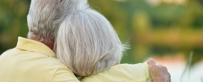ccrc move senior couple hugging in the park, back view