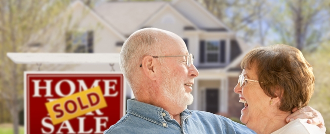 real estate market; couple with home sold sign