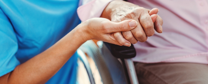 long-term care crisis Nurse consoling a senior woman in the nursing home holding her hand in the nursing home