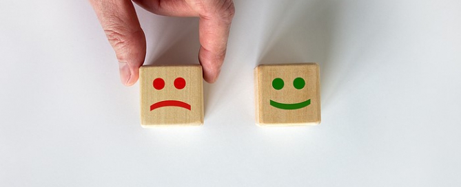life plan community management customer satisfaction; Close Up Hand Choose Smiley Face Icon On Wood Cube