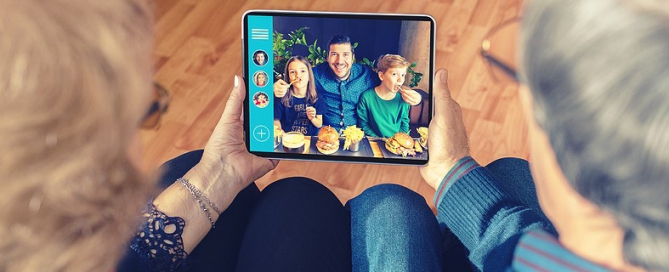 Senior Couple Video Chatting On Digital Tablet With Son And Grandkids seniors technology