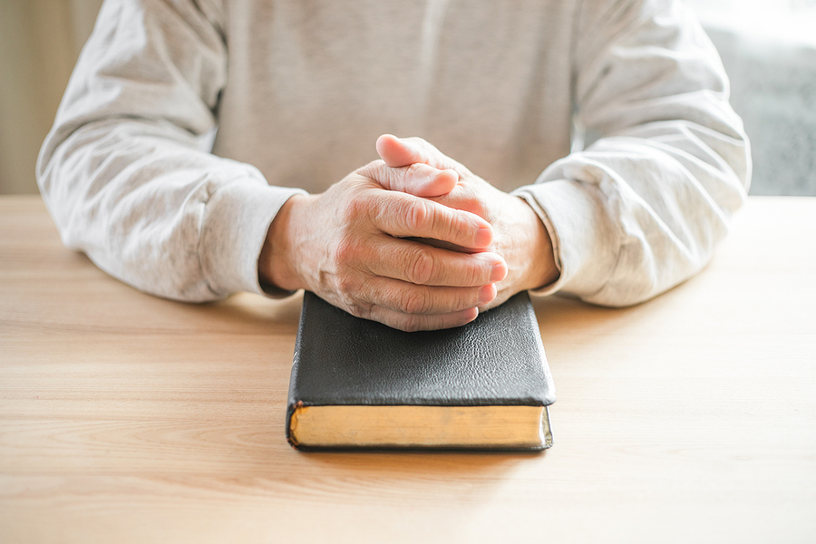 retired clergy housing allowance senior man praying with bible