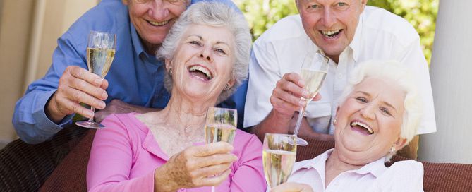Two senior Couples On Patio Drinking Champagne And Smiling; CCRC age