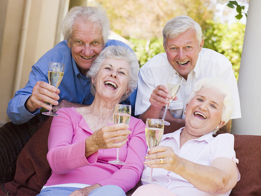 Two senior Couples On Patio Drinking Champagne And Smiling; CCRC age
