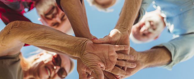 senior cohousing; group of seniors with hands stacked