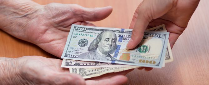 Elderly Man Gives Money From The Hands Of A Young woman pain of paying for long-term care