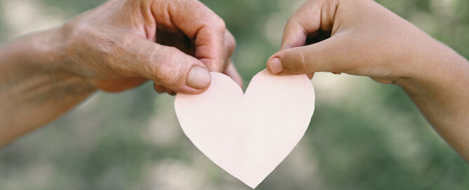 Childs Hand And senior Hand Grandmother Hold Heart. CCRC as community center