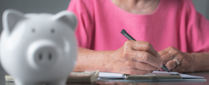 Finance And Savings Concept, Woman In Pink Shirt taking notes; middle-income seniors