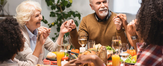 CCRC holiday traditions Family Holding Hands at Dinner On Thanksgiving Holiday