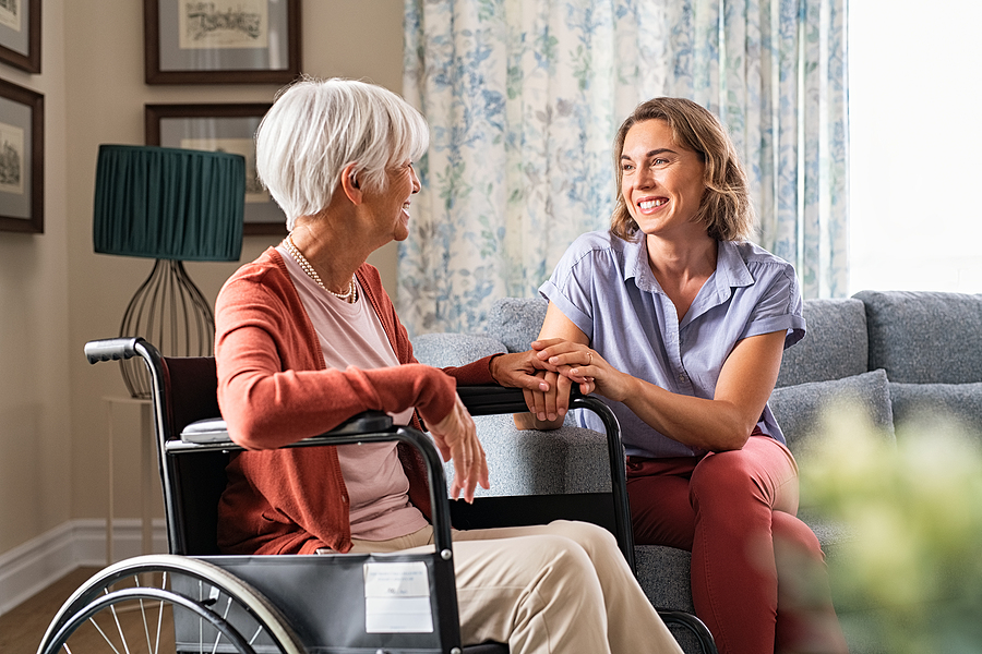 Mature woman comforting senior mom sitting on wheelchair assisted living medical mental health care needs