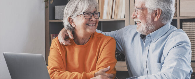 Happy Senior Couple Looking At Each Other Face To Face With Laptop CCRC marketing affordability