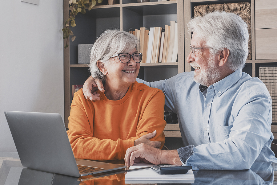 Happy Senior Couple Looking At Each Other Face To Face With Laptop CCRC marketing affordability