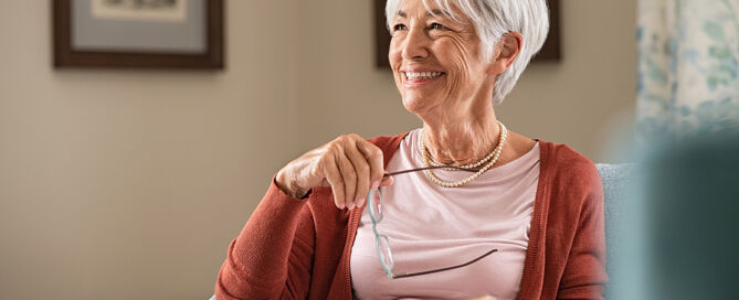 Senior woman holding eyeglasses thinking while relaxing at home CCRC wellness