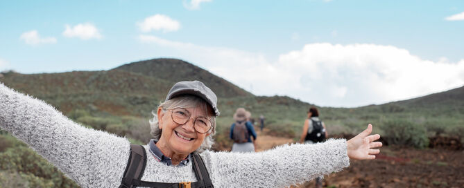 Senior Happy Woman With Backpack Walking In Countryside Footpath secret to healthy aging reverse aging