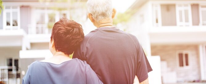 Happy Senior Couple Looking At Front Of retirement community building CCRC decision process