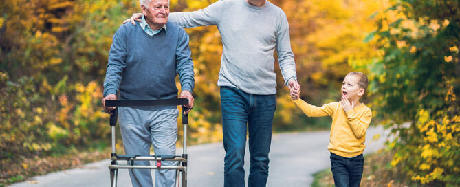 Elderly father adult son and grandson out for a walk in the park. sandwich generation aging parents