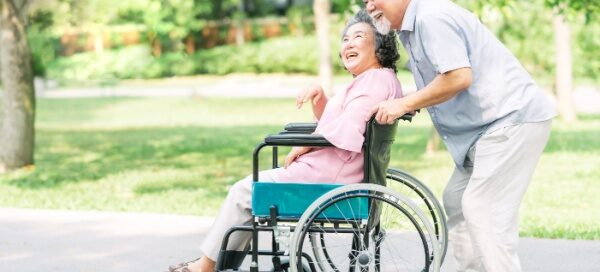 husband pushing wife in wheelchair _ CCRC fee adjustments