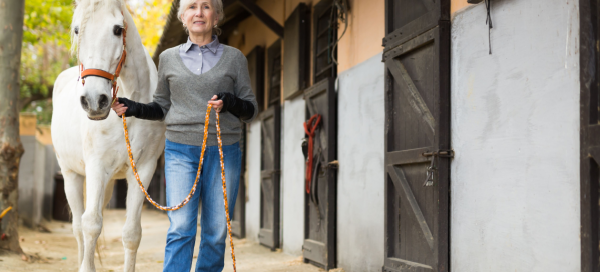 affinity retirement communities niche retirement communities; woman walking a horse by a stable