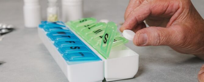 An,Elderly,Female,Hand,Places,One,Tablet,Into,A,Pill organizer; medication management issues