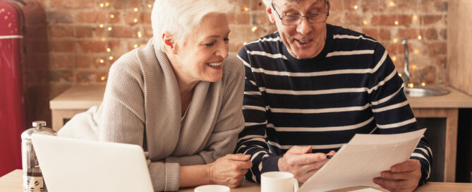 Smiling,Senior,Couple,Reading,Health,Insurance,Policy,Contract,In,Kitchen; lifecare community